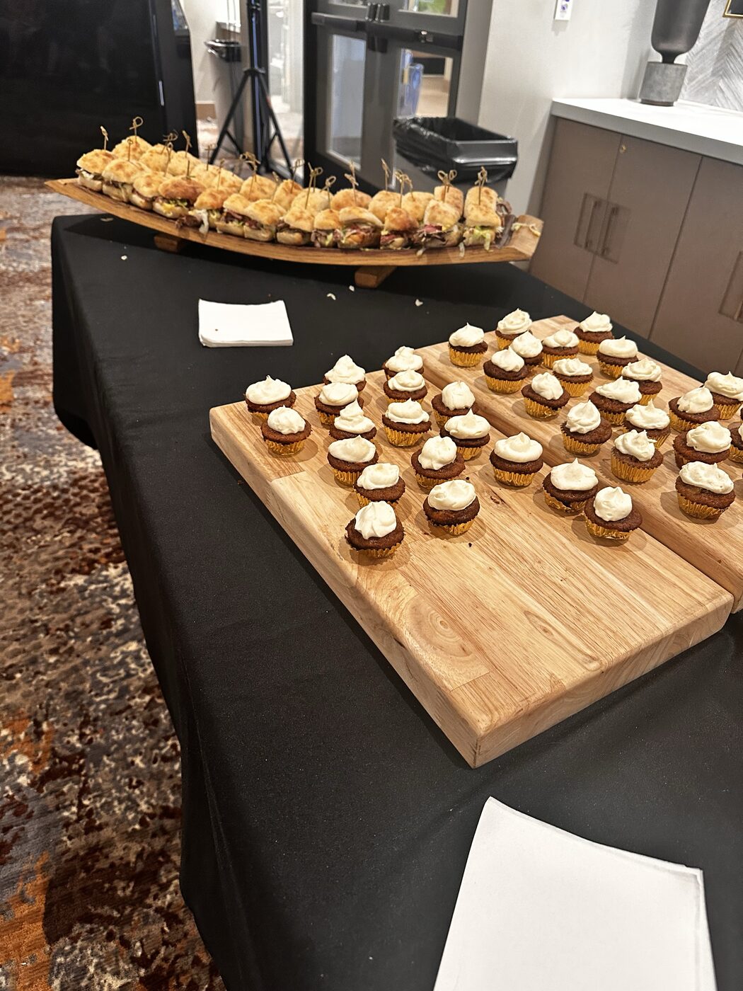A catered spread of gourmet sliders and decorated cupcakes